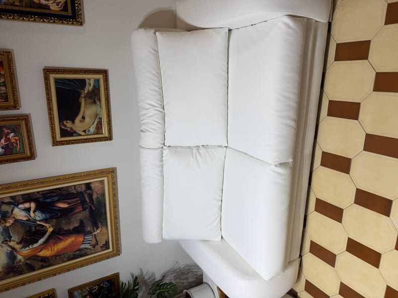 Sofá blanco tapizado en piel sintética en salón de Madrid